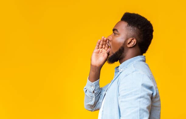 African american man making announcement, shouting at copy space Profile portrait of black guy making announcement, shouting at copy space on yellow studio background, sharing news. this side is for address only stock pictures, royalty-free photos & images