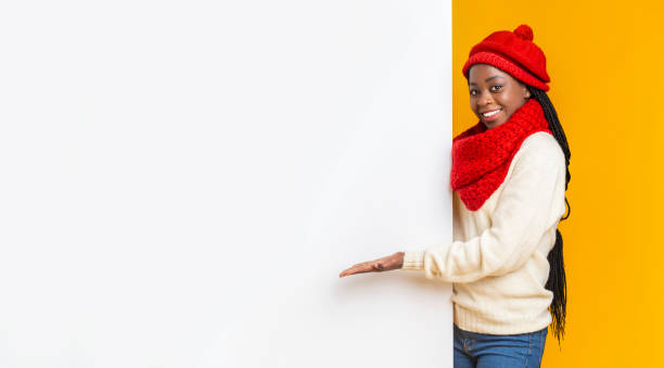 Black girl in winter set directing to blank board