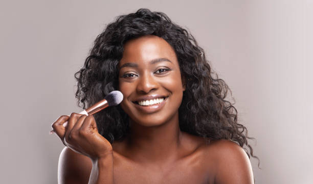 istock Beautiful african woman applying blush on face with brush tool 1184190070