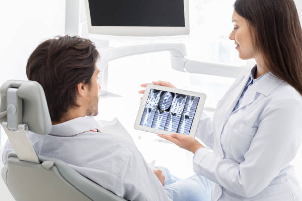 istock Female dentist showing patient x-ray results on digital tablet 1184190167