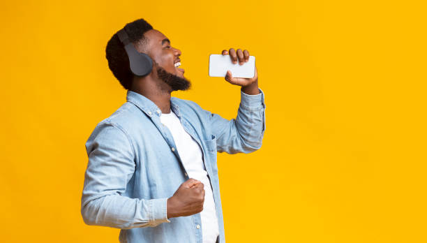 istock Cheerful african american man singing into smartphone like microphone 1184190944