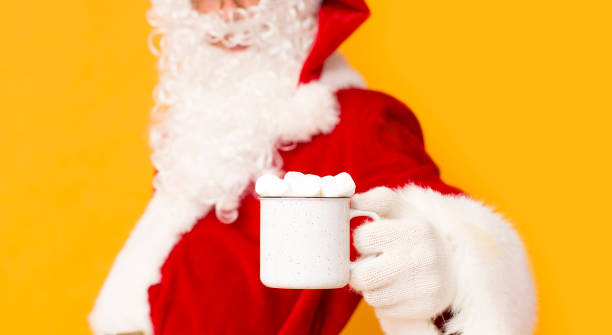 istock Blurred Santa Claus holding cup with marshmallows over orange 1184191133