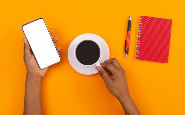 istock Afro female using smartphone with blank screen and drinking coffee 1184191155