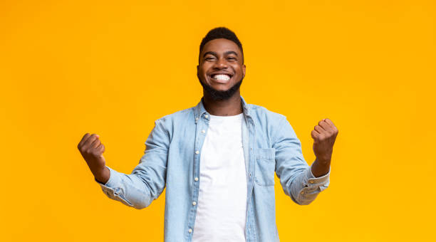 istock Joyful black guy rejoicing success with clenched fists 1184191270