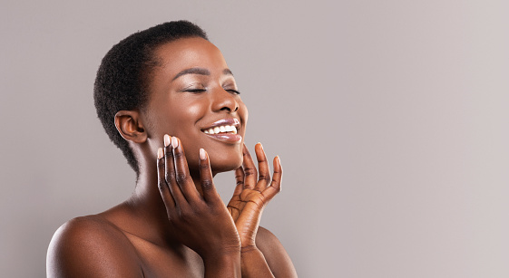 Feliz afro mujer tocando suave piel suave en su cara photo