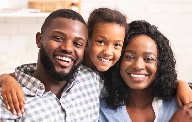 istock Black father, mother and daughter smiling and looking at camera 1184191846