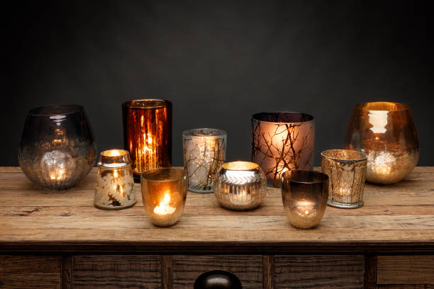 un gruppo di portacandele in vetro e candele incandescenti, girati su un tavolo di legno - tea light foto e immagini stock