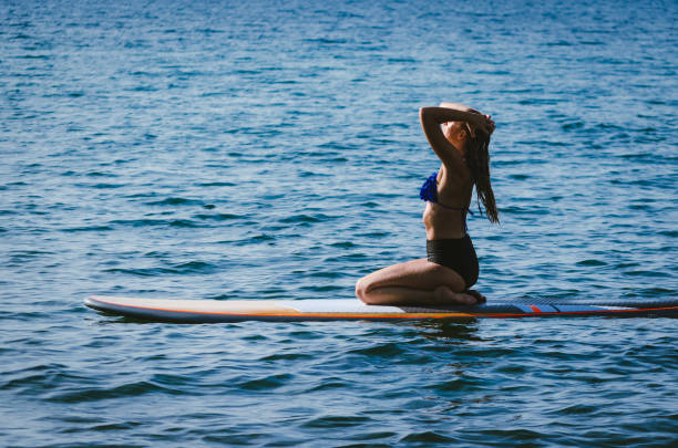 istock woman sitting on a sup touching her hair. 1184195964