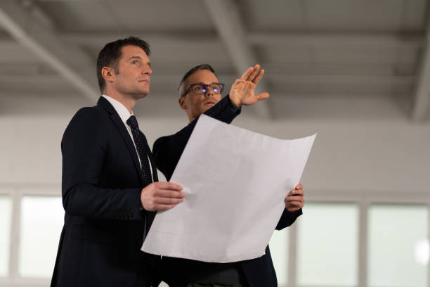 istock Businessmen discussing blueprint 1184196189