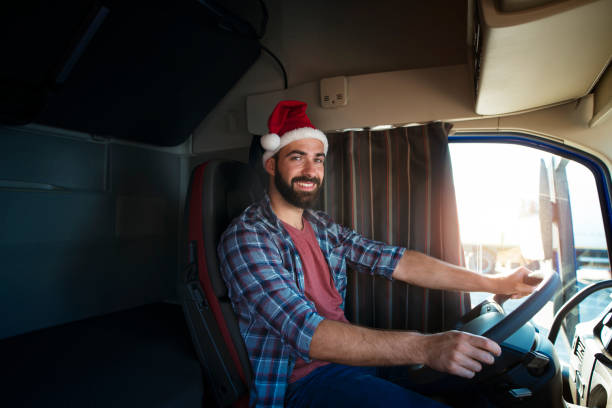 truck driver wearing santa clause hat and driving his truck on christmas. people working on holidays. trucker lifestyle. merry christmas. - truck driver highway truck working imagens e fotografias de stock