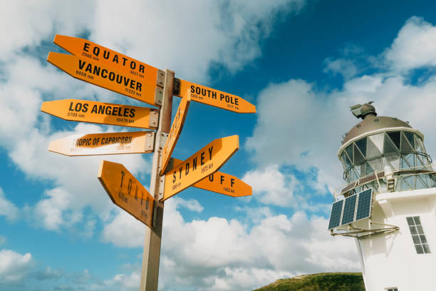 Cape Reinga Lighthouse and Sign Shot of a yellow signpost standing tall next to Cape Reinga Lighthouse, this is the furthest most northern point in New Zealand. tropic of capricorn stock pictures, royalty-free photos & images