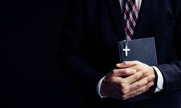 istock Man in black suit holding Bible 1184202955