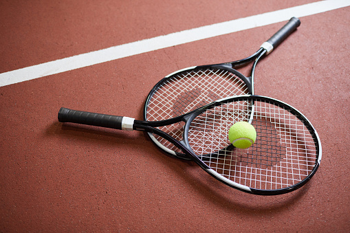 Primer plano de las raquetas negras modernas con bola verde claro que se encuentra en el suelo de la cancha de tenis, deporte y concepto de hobby photo
