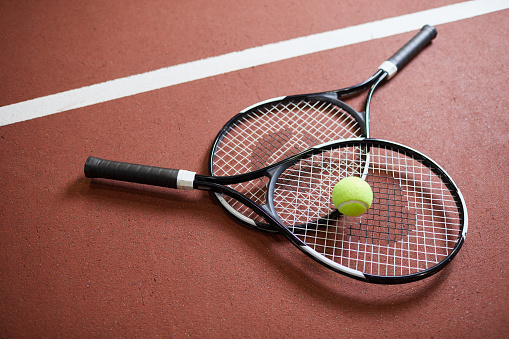 Three tennis balls on a tennis racket at the corner of the lines on blue tennis court. 3D rendering. Flat lay overhead view.