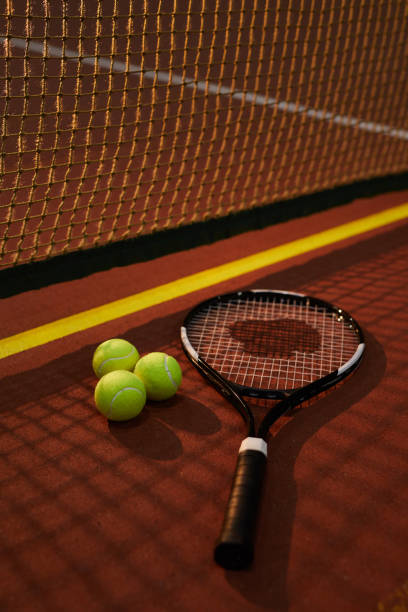 plan rapproché de raquette de tension de bien-corde et trois boules jaunes se trouvant sur le court de tennis foncé, ombre de l'effet de filet - racket string photos et images de collection