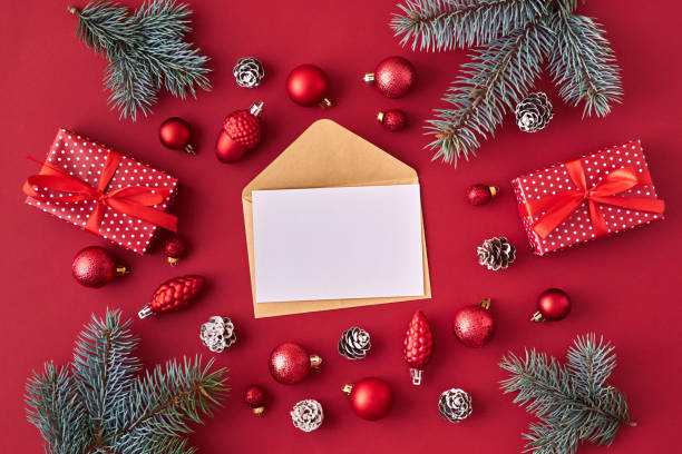 istock Mockup white greeting card and envelope with red christmas balls, spruce branches and gift box on a red background 1184207450