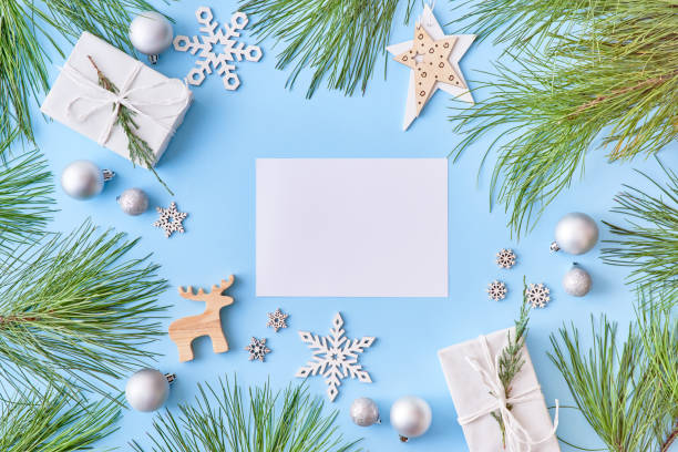 istock Mockup white greeting card with pine branches and gift box on a blue background 1184207465