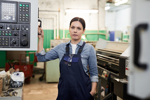 Serious lady in overall working at factory