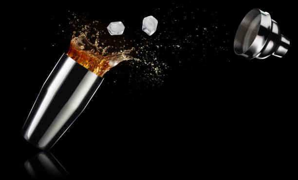 amber liquid splashing out of a shaker on black background ice cubes and cocktail spilling out of a shaker isolated on black background amber black photography stock pictures, royalty-free photos & images