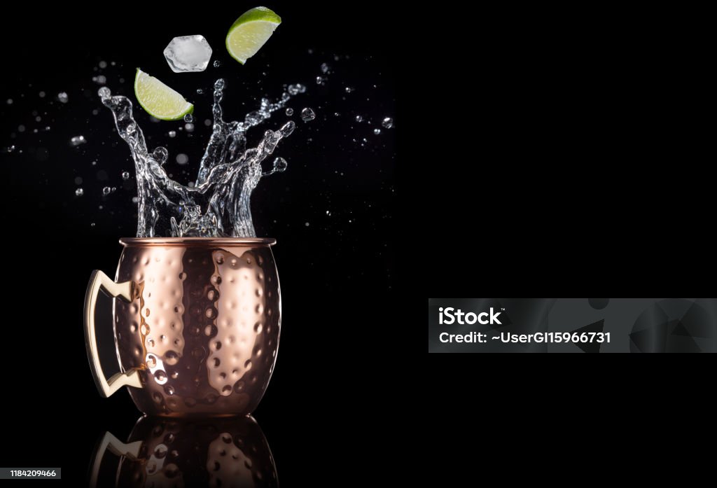 moscow mule splashing on black background lime and ice falling into a splashing moscow mule cocktail isolated on black background Moscow Mule Stock Photo