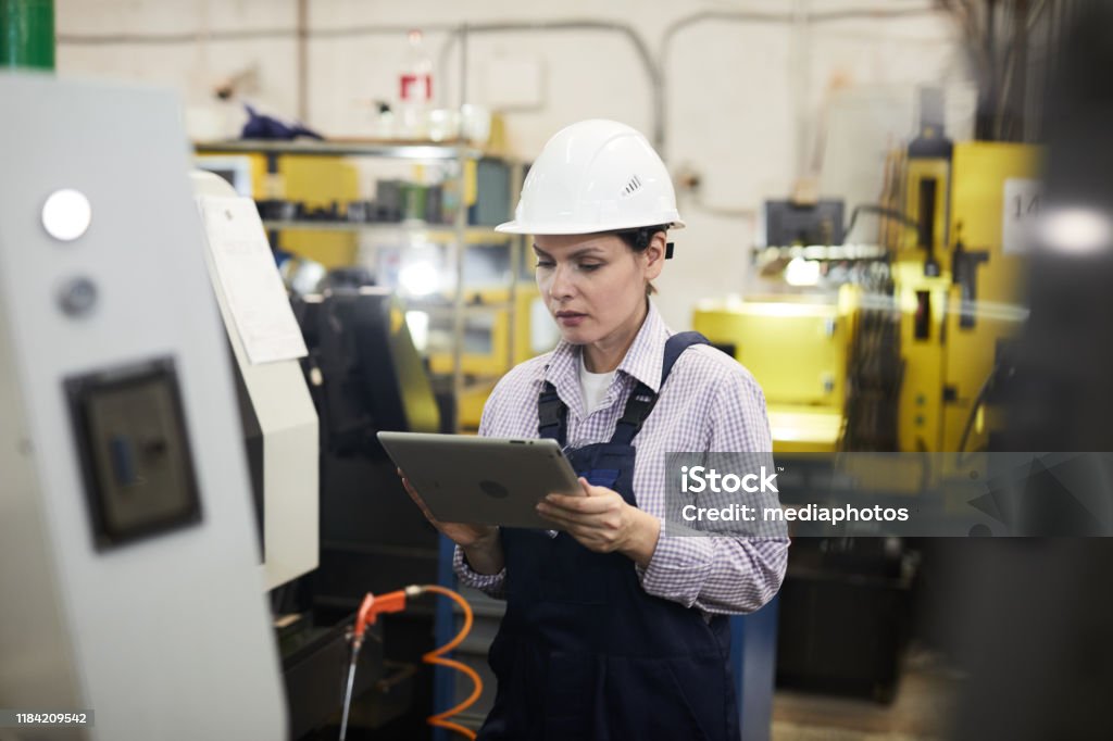 Operador De Máquina Cnc Joven Concentrada En Hardhat De Pie En Torno Industrial Y Configuraciones De Comprobación En La Tableta Digital Foto de stock y más banco de imágenes de Tableta digital - Operador De Máquina Cnc Joven Concentrada En Hardhat De Pie En Torno Industrial Y Configuraciones De Comprobación En La Tableta Digital Foto de stock y más banco de imágenes de Tableta digital -