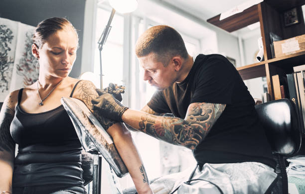 istock Artist Tattooing woman's shoulder 1184211334