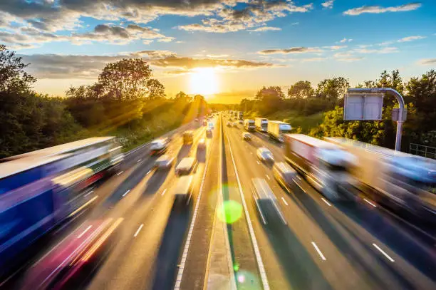 heavy traffic moving at speed on UK motorway in England at sunset.