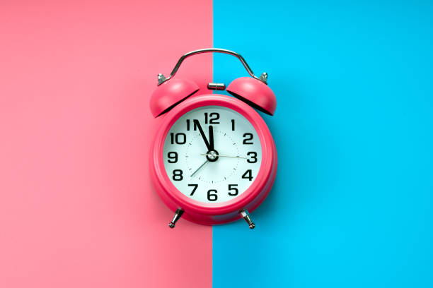 istock pink  alarm clock on pink blue background 1184213532