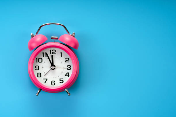 istock pink alarm clock on blue background 1184213611