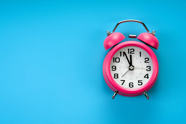 istock pink alarm clock on blue background 1184213623