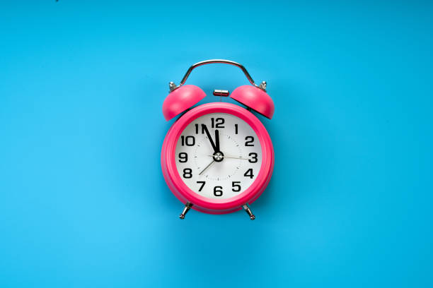 istock pink alarm clock on blue background 1184213739