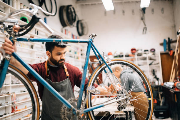 Bike shop owner working on vintage bicycle Bike shop owner repairing a vintage bicycle bicycle shop stock pictures, royalty-free photos & images
