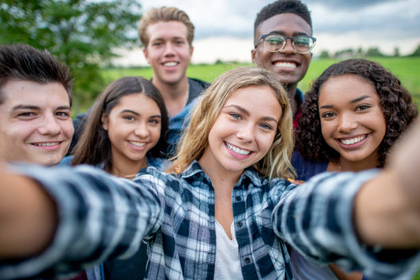 Multi_ethnic Teenagers Taking a Self Portrait stock photo A group of multi-ethnic students taking a selfie outside. They are dressed casually and having fun together in a group. 14 15 years photos stock pictures, royalty-free photos & images