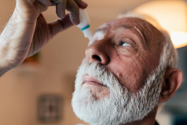 hombre mayor usando gotas para los ojos - pain human eye senior adult men fotografías e imágenes de stock