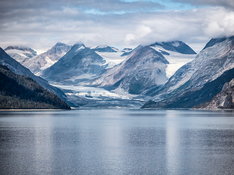 Elevated telephoto view of snow covered mountains and entrance to Tidal Inlet in Alaska’s Glacier Bay National Park.