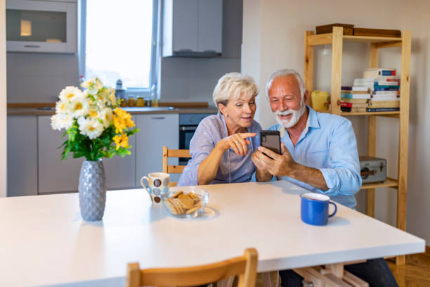 istock Elderly couple sitting on table with smartphone discuss new application 1184218602
