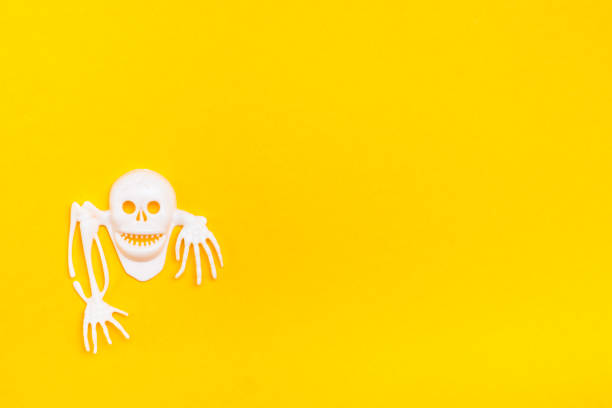 istock White plastic skull with bones on a yellow cardboard background. Ready Halloween illustration 1184220000