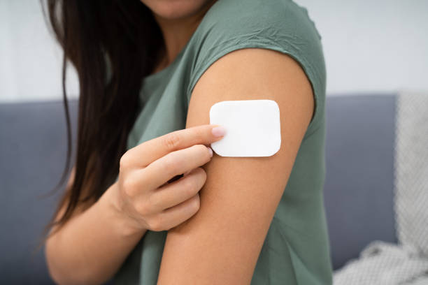 Woman Applying Patch On Her Arm Woman Applying Patch On Her Arm At Home estrogen photos stock pictures, royalty-free photos & images
