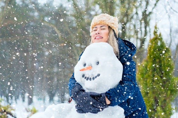 Asian woman enjoying with snow, making snowman in woods