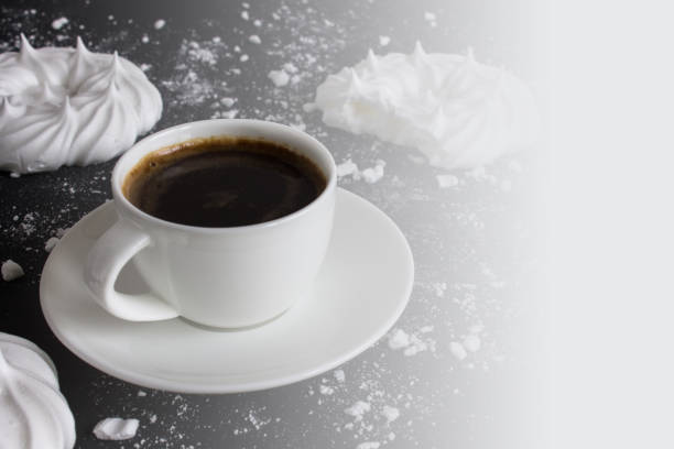 istock Cup of coffee and meringue on black background 1184227608