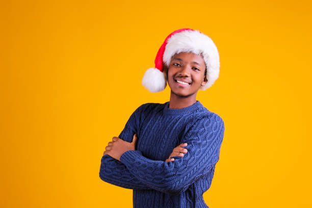 istock Young black male in santa hat posing over yellow background. 1184228720