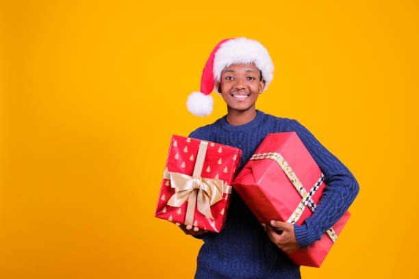 istock Young black male in santa hat posing over yellow background. 1184228742