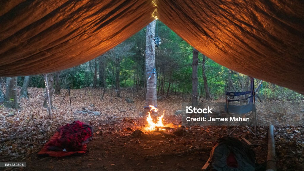 Primitive Tarp Shelter with campfire and fairy lights. Survival Bushcraft setup in the Blue Ridge Mountains near Asheville. During autumn / fall season. Tarpaulin Stock Photo