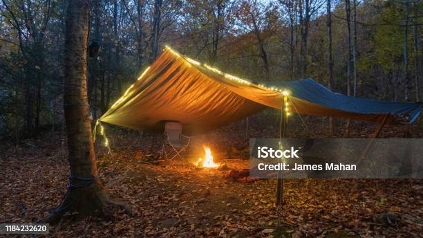 Primitive Tarp Shelter With Campfire And Fairy Lights Survival Bushcraft Setup In The Blue Ridge Mountains Near Asheville During Autumn Fall Season Stock Photo - Download Image Now