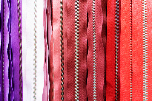 Abundance of zippers in red, purple, pink, white in a row.