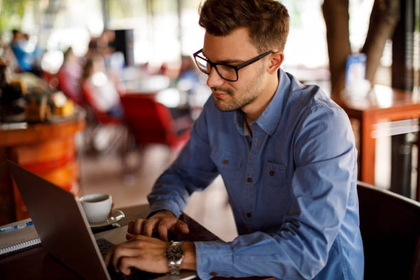 istock Young man sitting in coffee shop and using laptop 1184238350