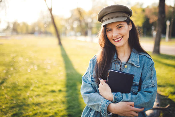 istock Woman holding book in public park 1184239676
