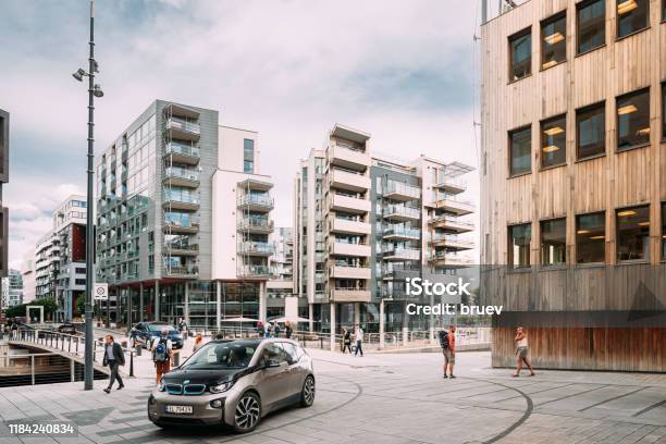Oslo Noruega Personas Caminando Cerca De Casas Residenciales De Varios Pisos En El Distrito De Aker Brygge En La Noche De Verano Lugar Famoso Y Popular Foto de stock y más banco de imágenes de Coche eléctrico - Coche alternativo