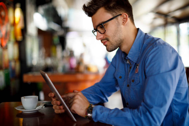 молодой человек с помощью цифрового планшета в кафе - e reader digital tablet cafe reading стоковые фото и изображения