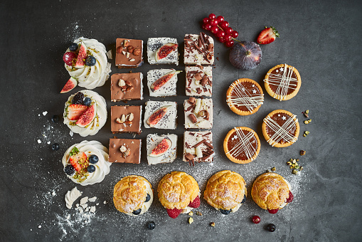 Assortment of freshly-made cakes and desserts sitting in a glass display counter in an artisanal bakery and cafe
